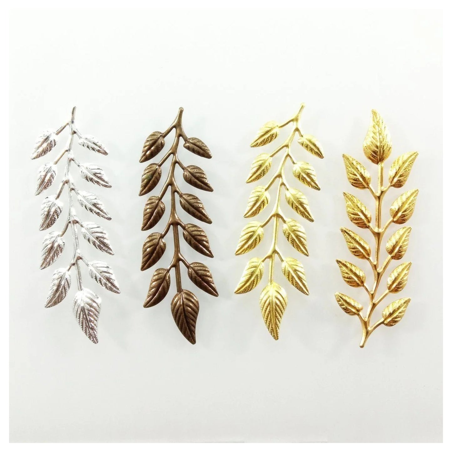 Set of leaf-shaped decorative items in silver, bronze, gold and brass colours on white background