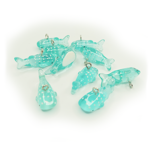 Set of turquoise dolphin-shaped charms on a white background