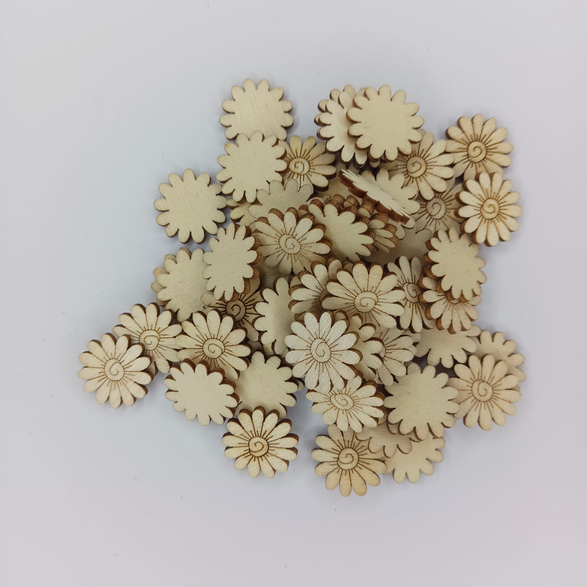 A pile of small natural wood flower-shaped craft pieces on a plain light background.