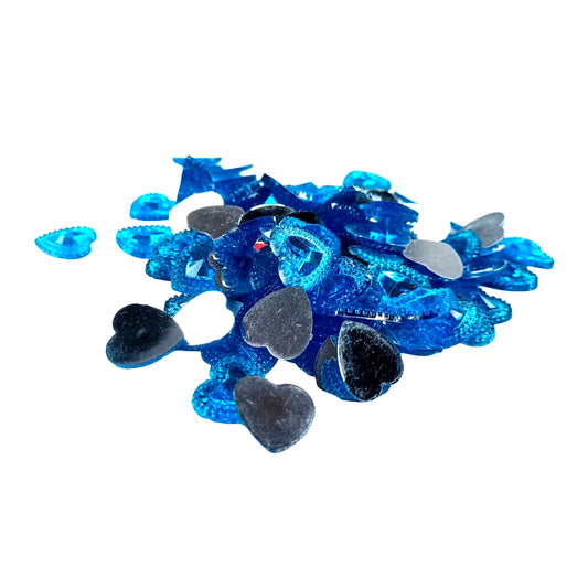 A pile of small heart-shaped craft embellishments in metallic blue, silver, and white, scattered on a plain white background