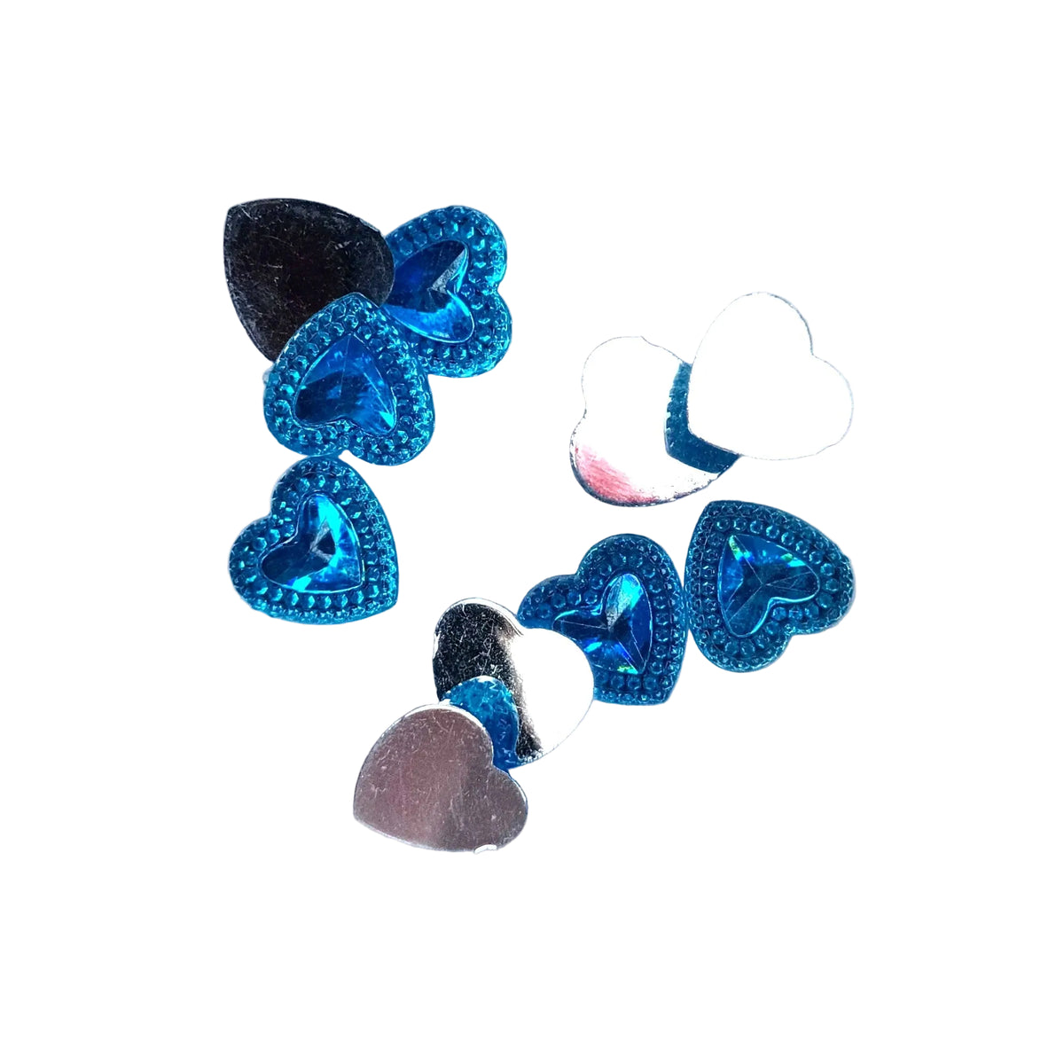 A group of small heart-shaped craft embellishments in metallic silver, blue, and white, arranged on a plain gray background.