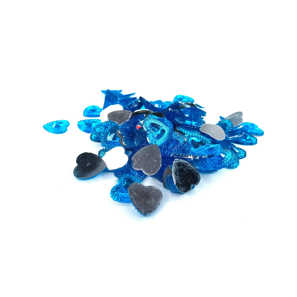A pile of small heart-shaped craft embellishments in metallic blue, glittery blue, black, and white, scattered on a plain light gray surface.