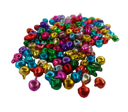 A pile of small metallic jingle bells in assorted bright colors, including pink, blue, green, yellow, orange, and silver, scattered on a plain white background.