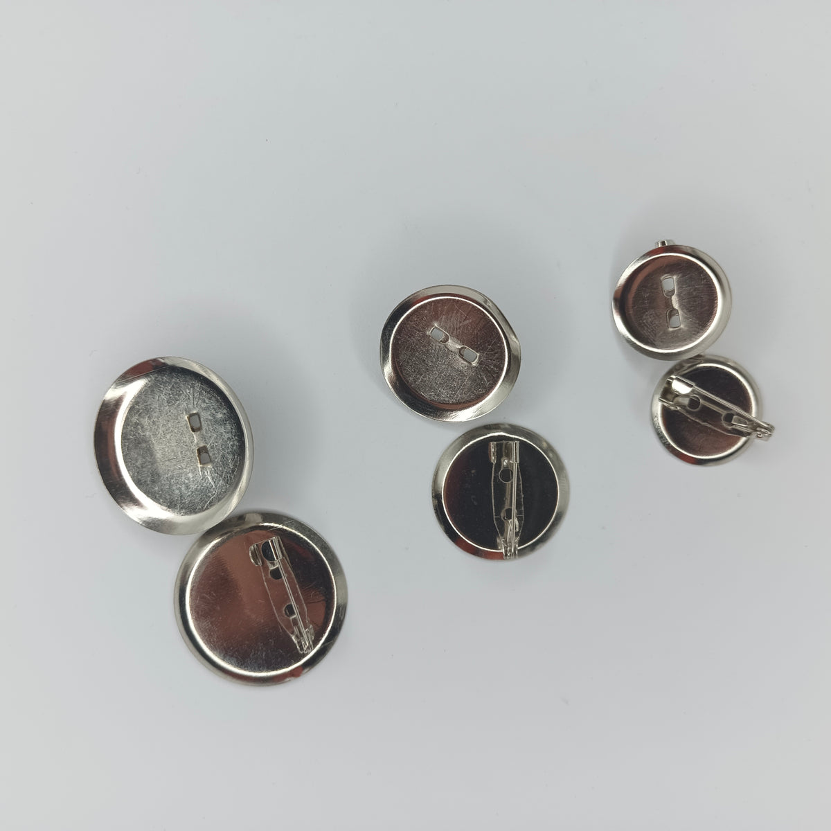 Five silver metal pin-back cabochon holders shown from the back on a light gray background.
