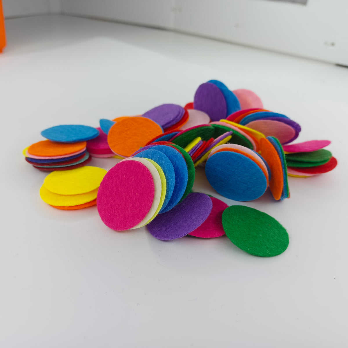 A pile of colorful oval felt pieces in various shades including pink, blue, green, yellow, orange, purple, and red, arranged on a white surface.