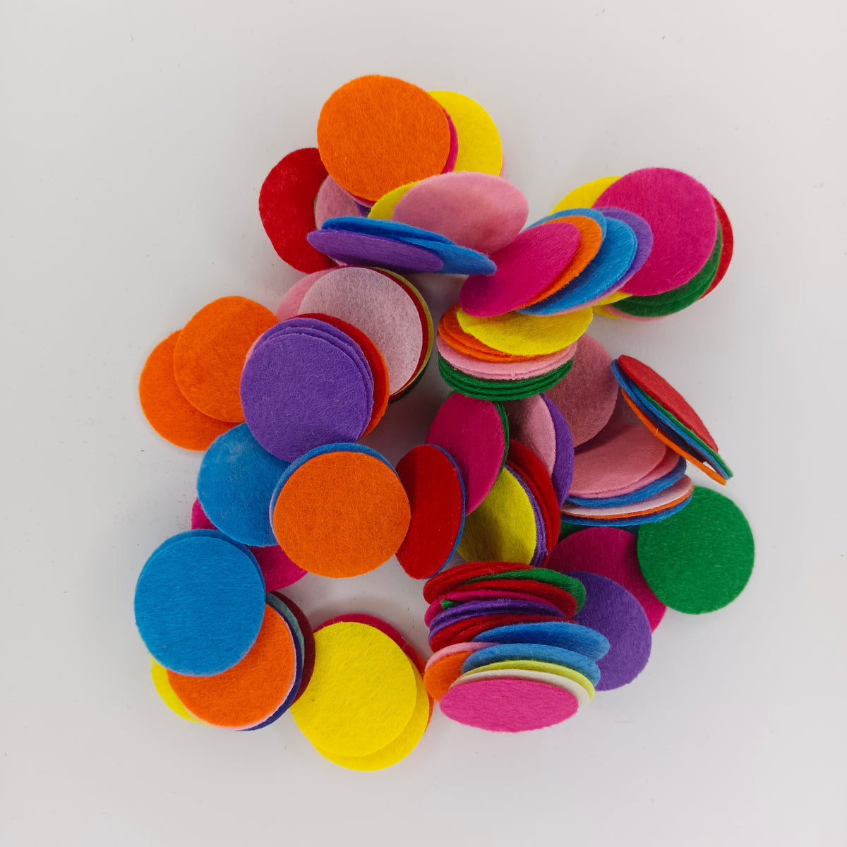 A pile of colorful round felt cutouts in shades of orange, yellow, pink, blue, purple, red, and green on a plain white background.