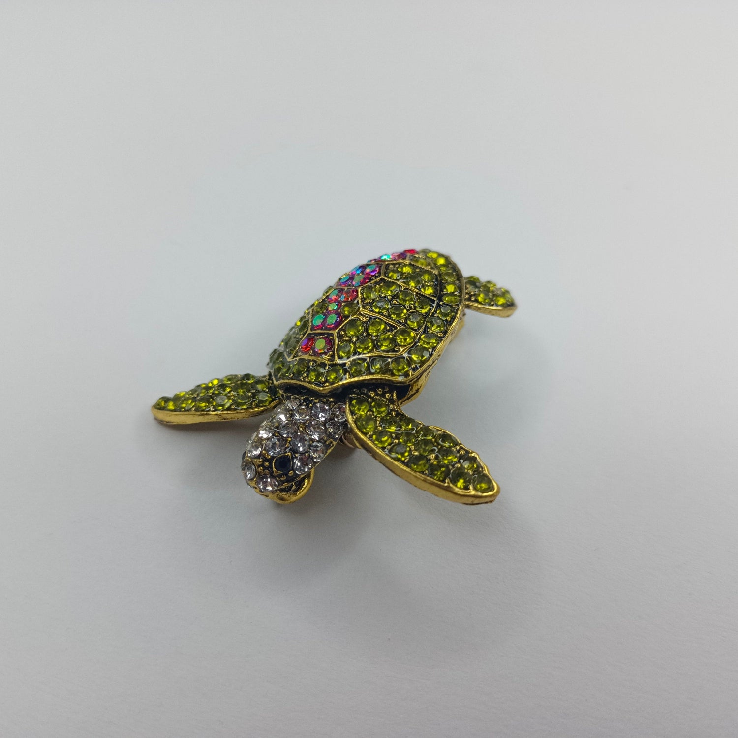 Decorative turtle figurine with gemstone details on a light gray background