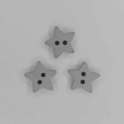 Three small gray wooden star-shaped buttons with two holes, arranged in a triangle on a plain white background.